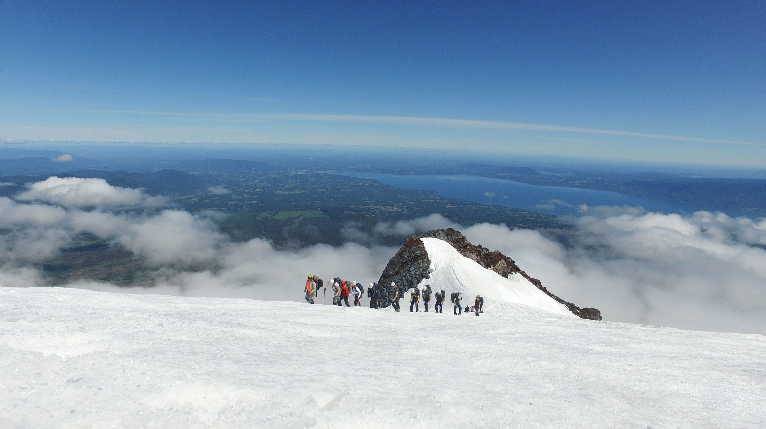 Grupo de Pucón Travel en la cumbre del volcán Villarrica con el lago Villarrica al fondo